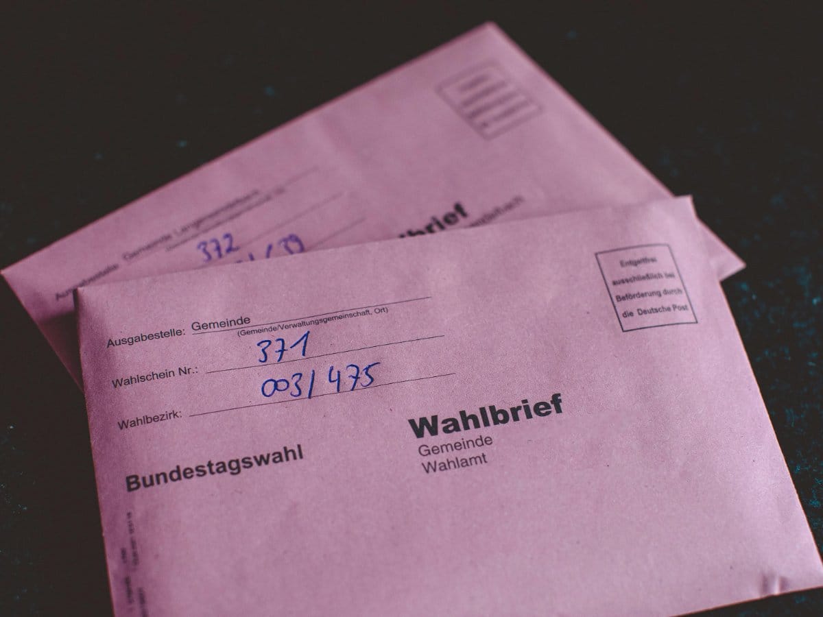 A high-volume Chicago distribution center workbench with digital calipers, postage rate charts, and a variety of envelope types paired with correct stamp denominations.